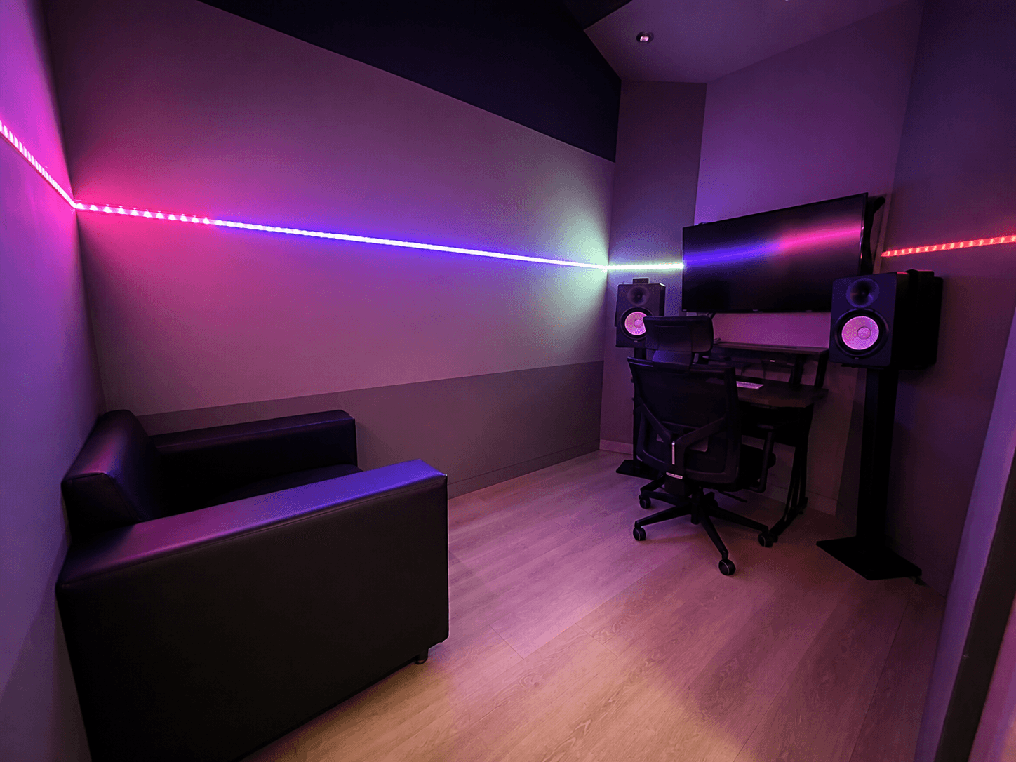 A Room with a production workstation, studio monitors, seating, and violet lighting