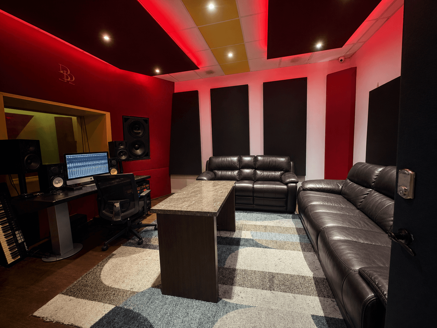 B Room with red acoustic panels, production workstation, and lounge seating